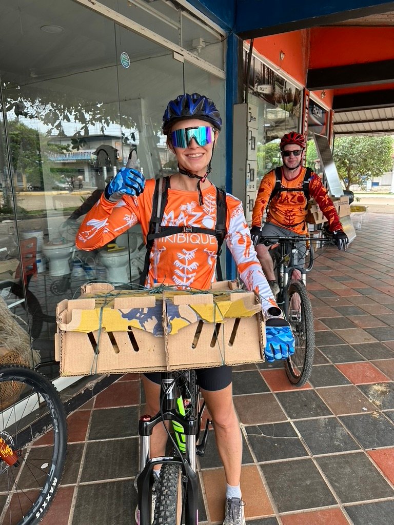 Expedition riders loading 100 baby chicks onto their bikes for delivery to a Nukak community