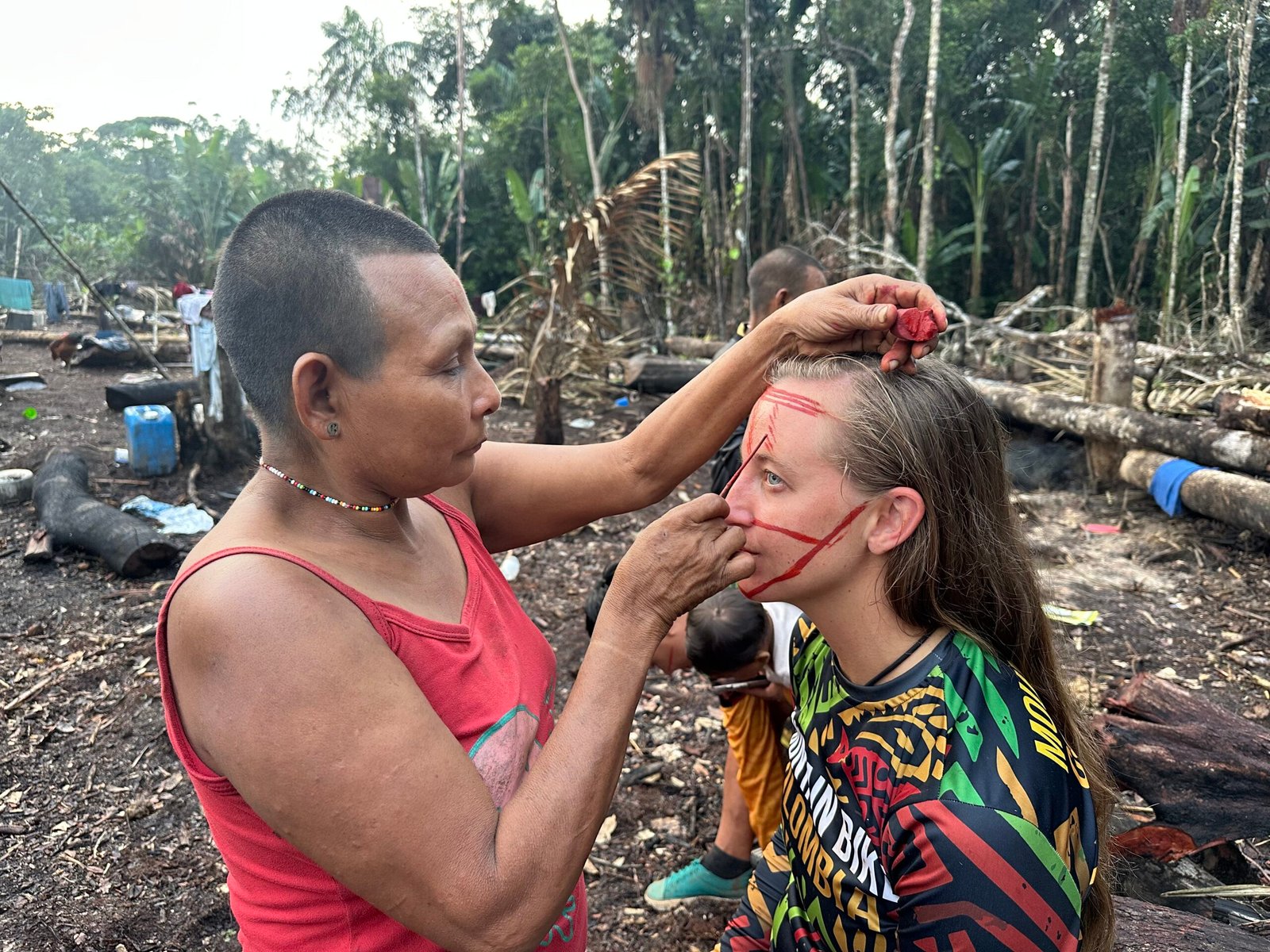 Nukak woman applying traditional face paint to an expedition rider