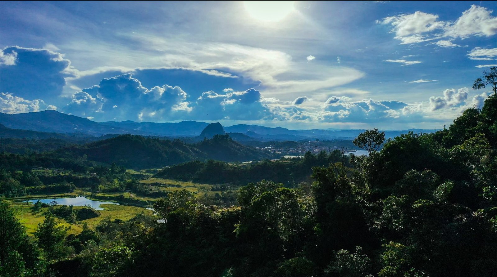 The Guatapé basin from the forested hills above town, with the reservoir and La Piedra del Peñol in the distance