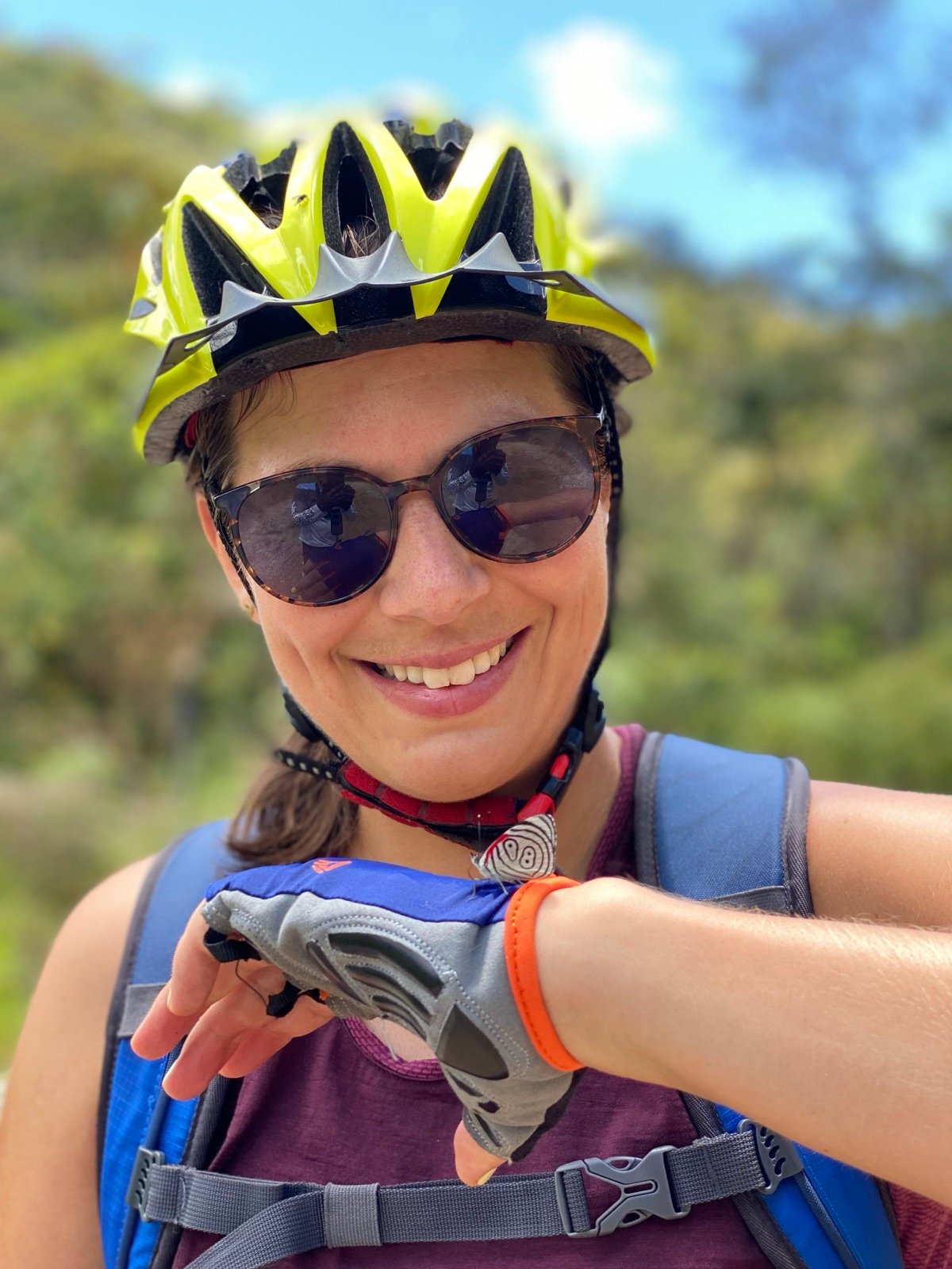 Smiling rider in a helmet and sunglasses with an 88 butterfly, a Diaethria, resting on her glove